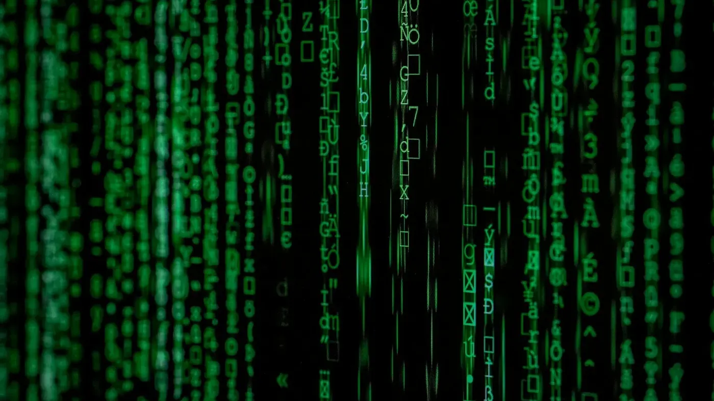 Vertical lines of cascading green computer code and symbols against a black background, representing digital data.