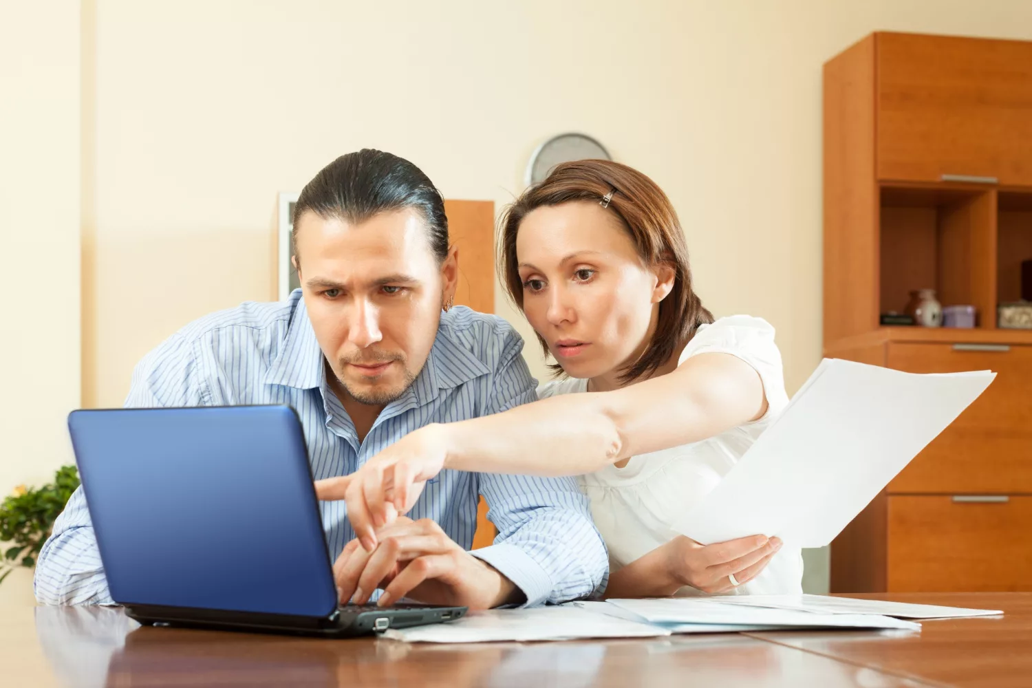 Two people discussing business insurance budgeting for startups while working on a laptop in an office setting.